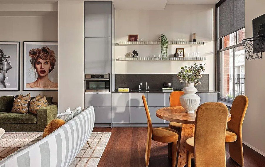 Lounge with a kitchenette, dining table and velvet chairs beside tall windows