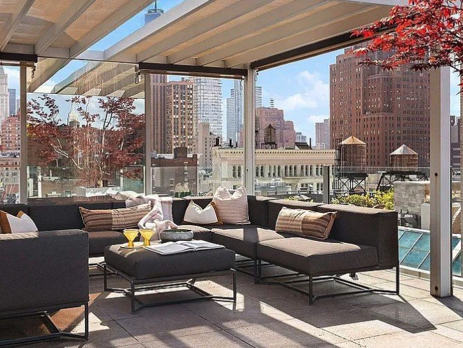 Covered roof terrace lounge with a sectional sofa and views over SoHo water towers