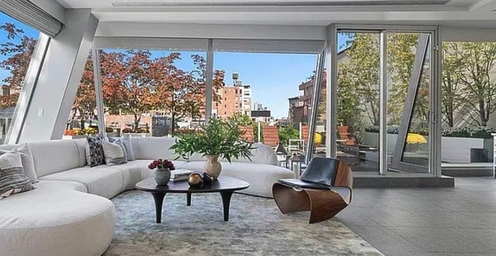 Glass-walled living room opening through sliding doors onto a planted terrace